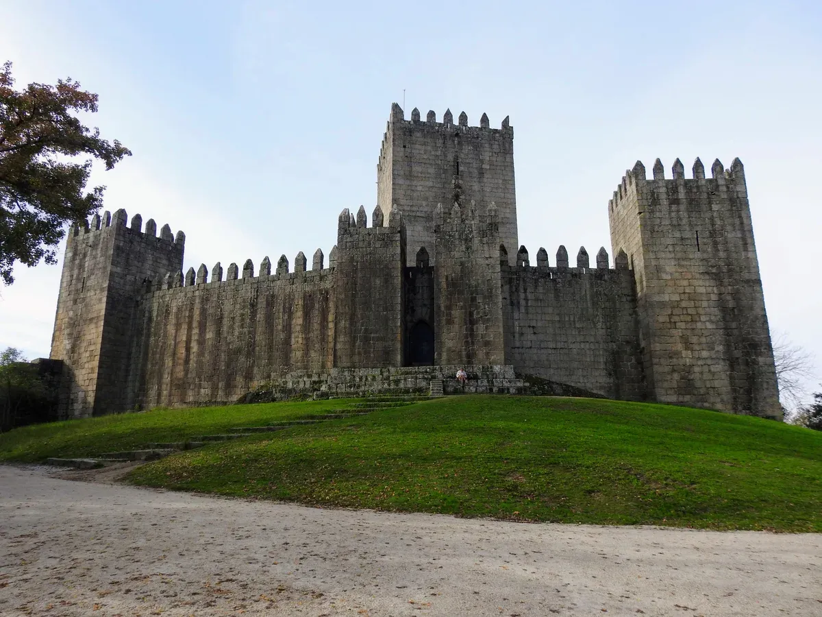 The keep and walls of Guimarães Castle on its green hill, a day trip from Porto by train